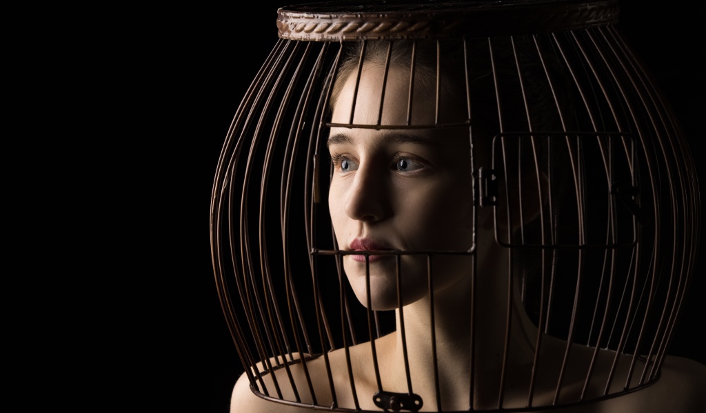 Молодая девушка с клеткой на голове 