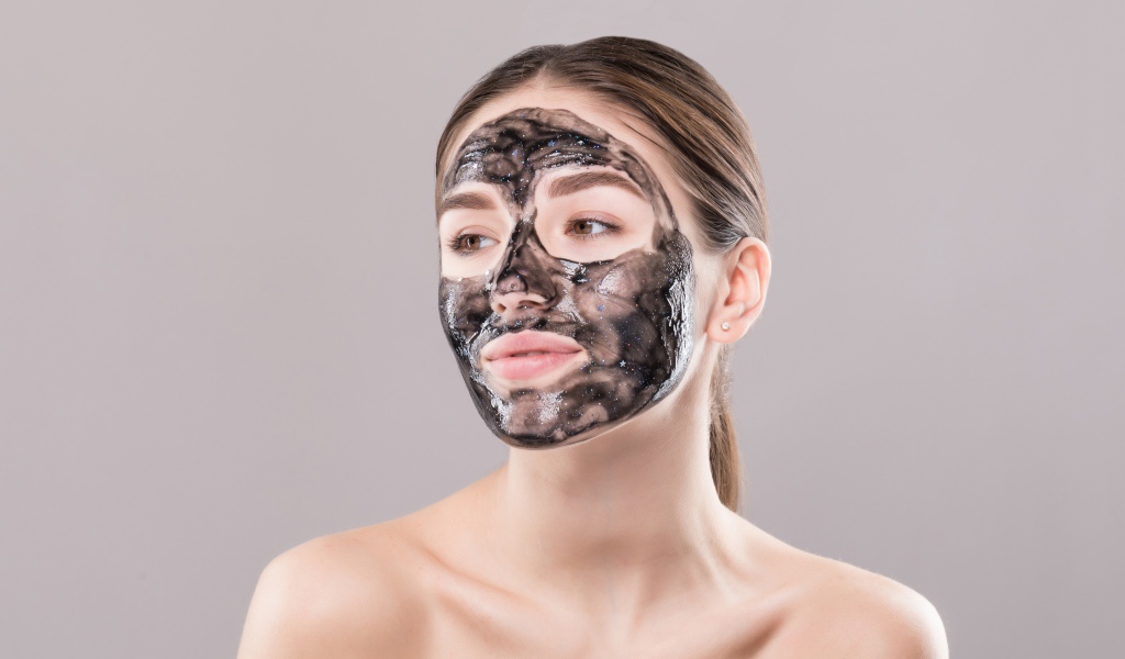 Молодая девушка с косметической черной маской на лице