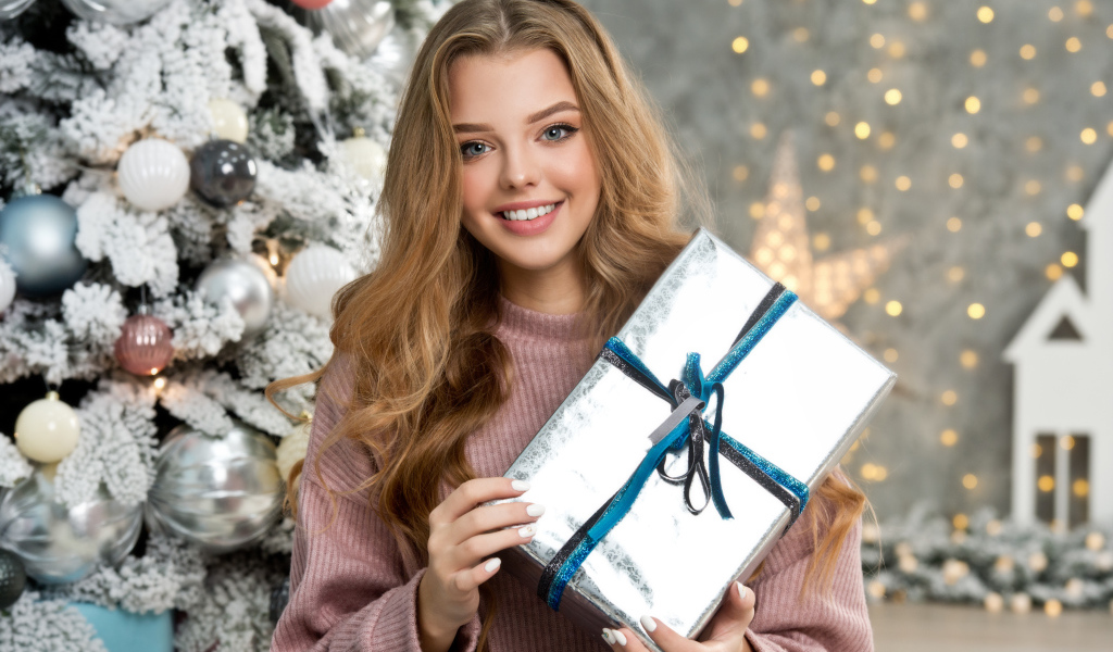 Красивая девушка с подарком у елки на новый год 