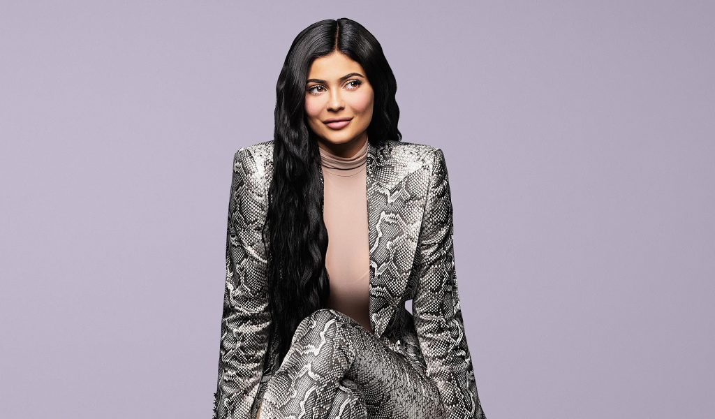 Длинноволосая модель Кайли Дженнер в костюме на сером фоне