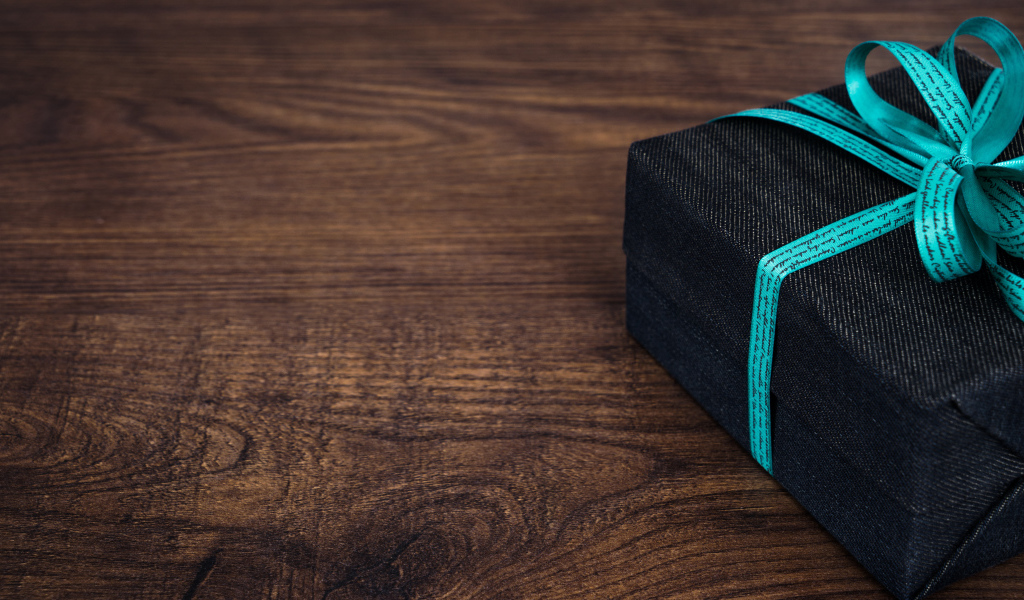 Подарок с синим бантом на деревянном столе 