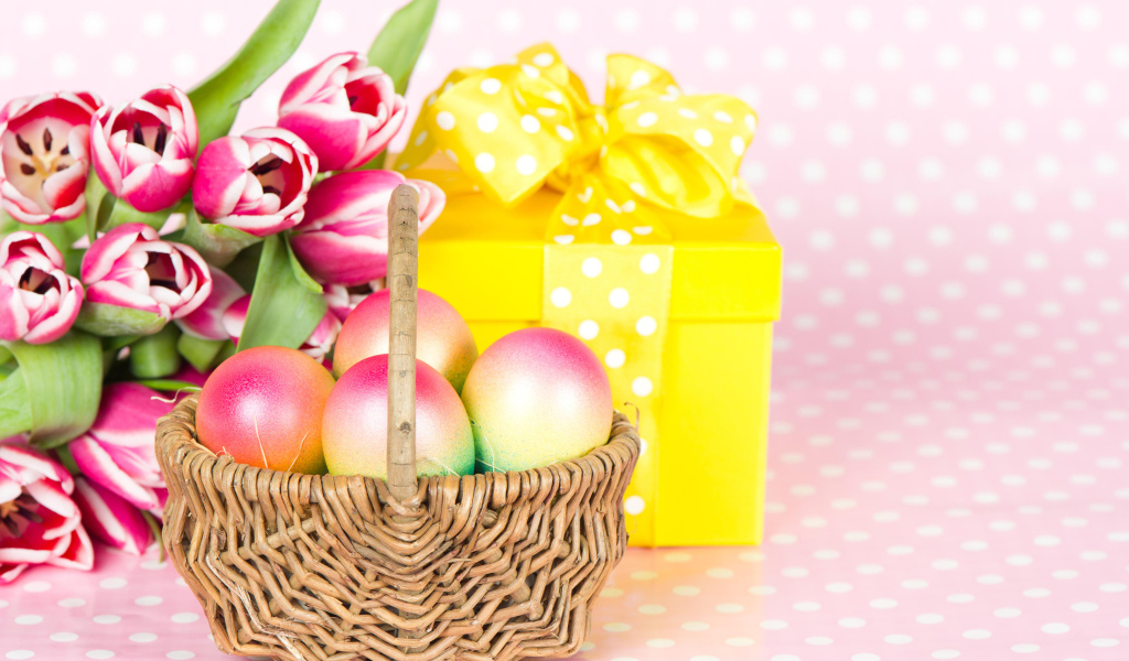 Корзина с пасхальными яйцами на столе с подарком и букетом тюльпанов 