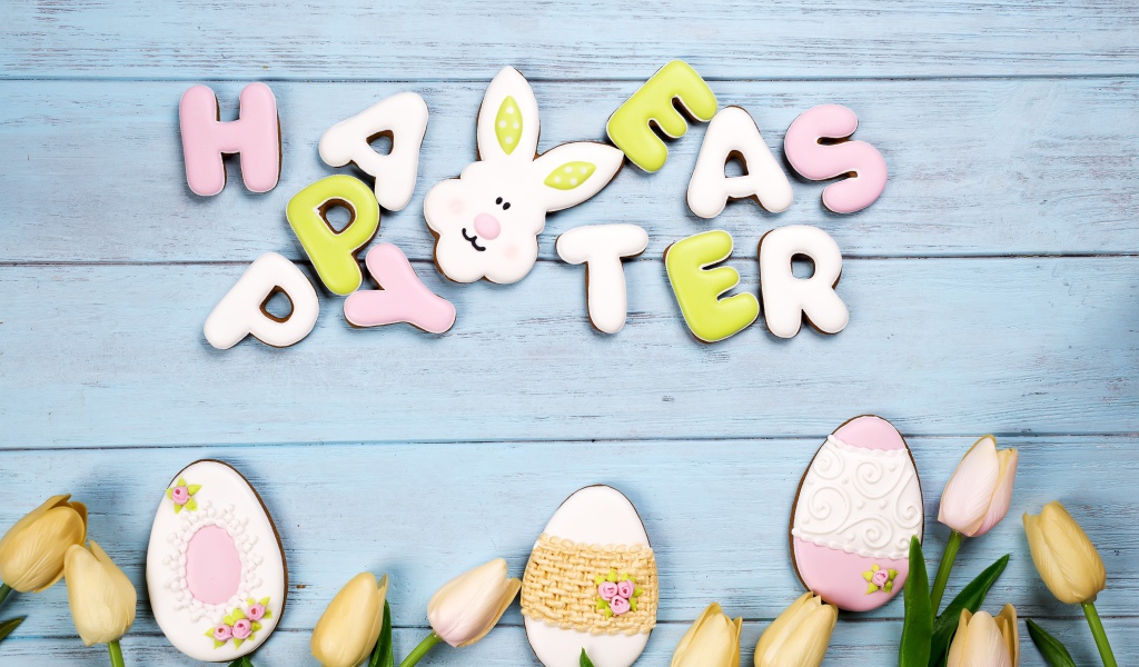 Красивое пасхальное печенье на столе с тюльпанами 