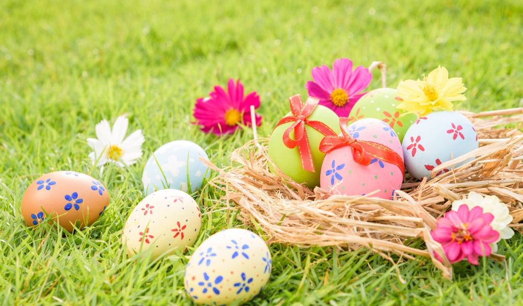 Разноцветные яйца в гнезде на зеленой траве на Пасху