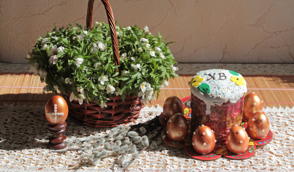 Пасхальный кулич с яйцами на столе с корзинкой цветов на праздник