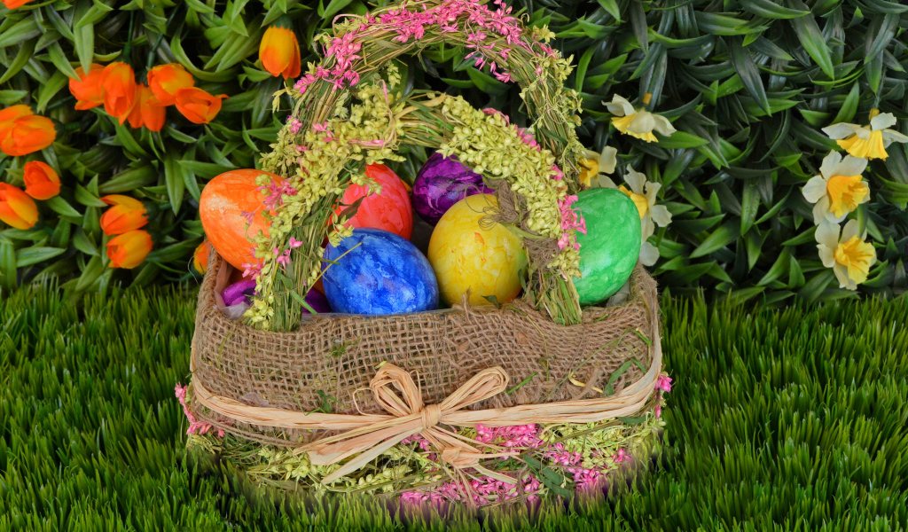 Разноцветные пасхальные яйца в корзине на зеленой траве на праздник 