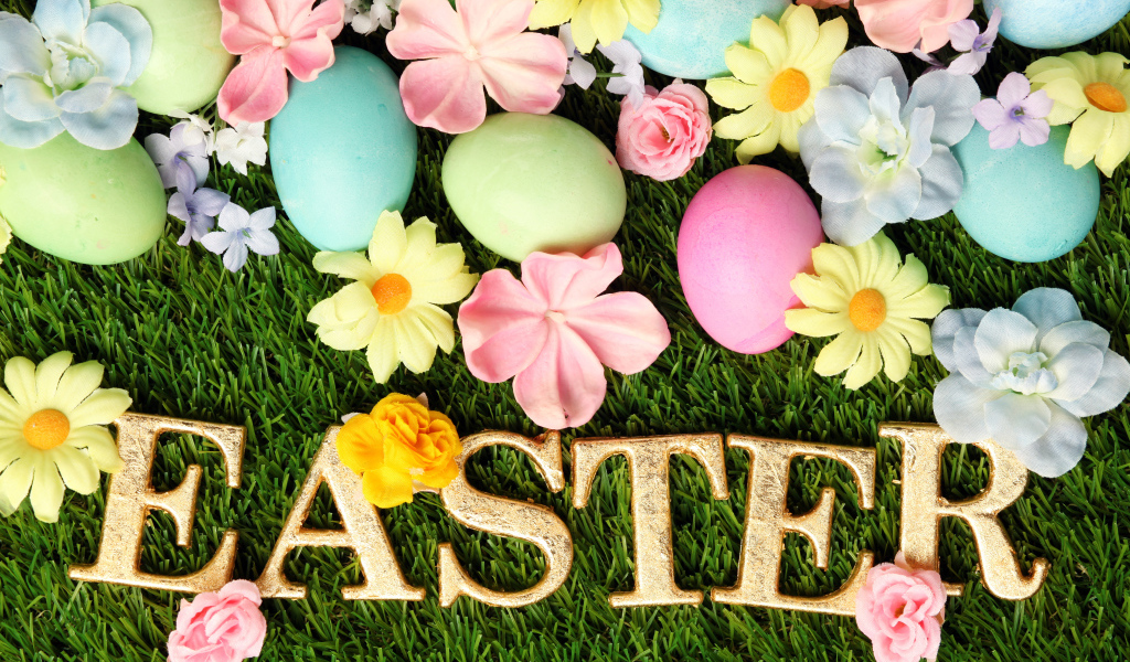 Надпись на траве с разноцветными яйцами и цветами на Пасху