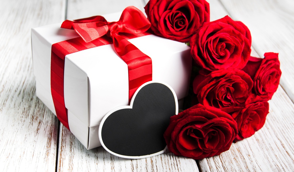 Букет красивых красных роз на столе с подарком для любимой на 8 марта