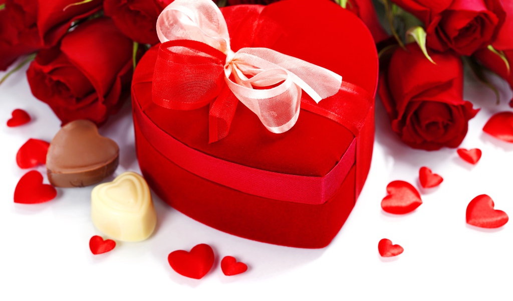 Красная коробка в форме сердца на столе с розами и конфетами для любимой