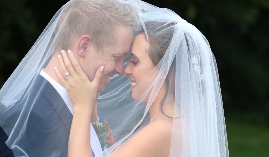Жених и невеста стоят под белой фатой