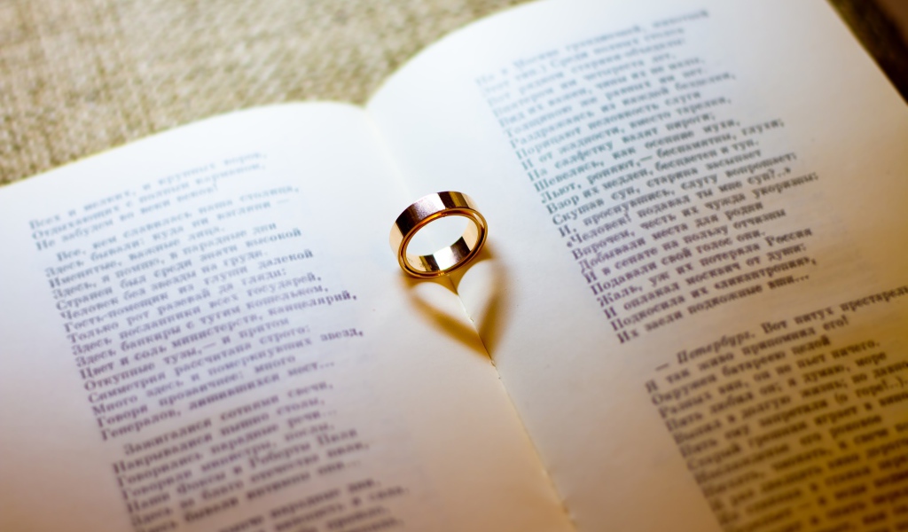 Золотое обручальное кольцо лежит на открытой книге