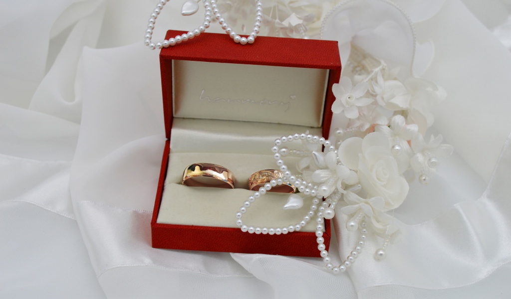 Золотые обручальные кольца в красной коробочке с украшениями