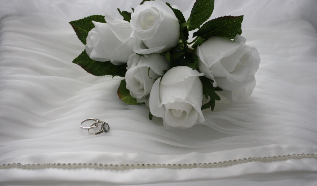 Белые бутоньерки с кольцами на белом покрывале 