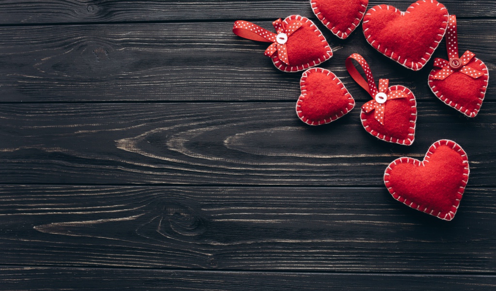 Много красных сердечек из фетра на деревянном столе