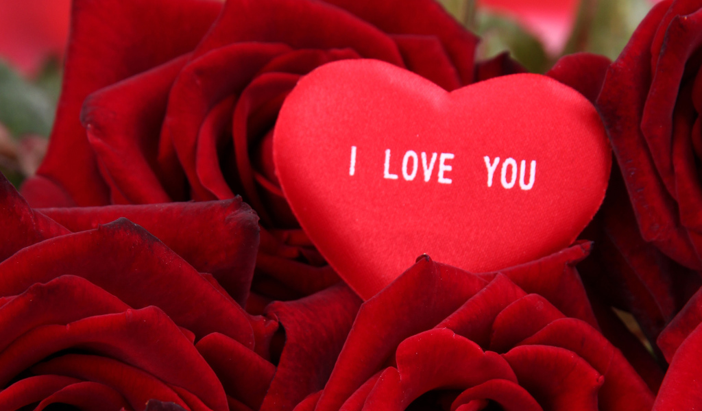 Маленькое сердце лежит на букете красных роз 