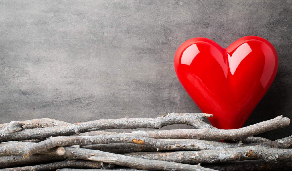Большое красное сердце на сером фоне с деревянными прутьями