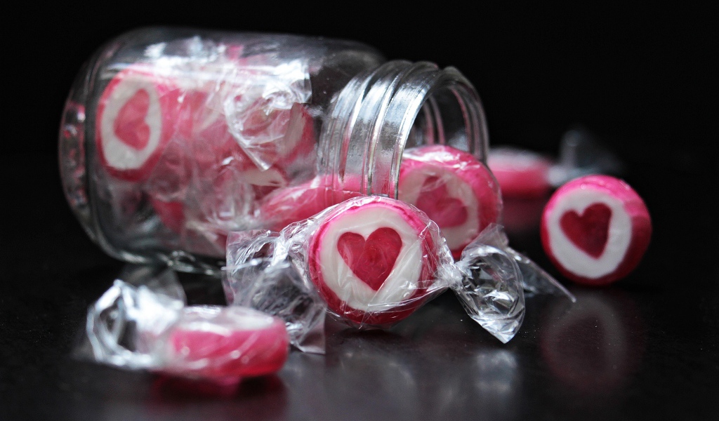 Конфеты с сердцем в стеклянной банке на черном фоне