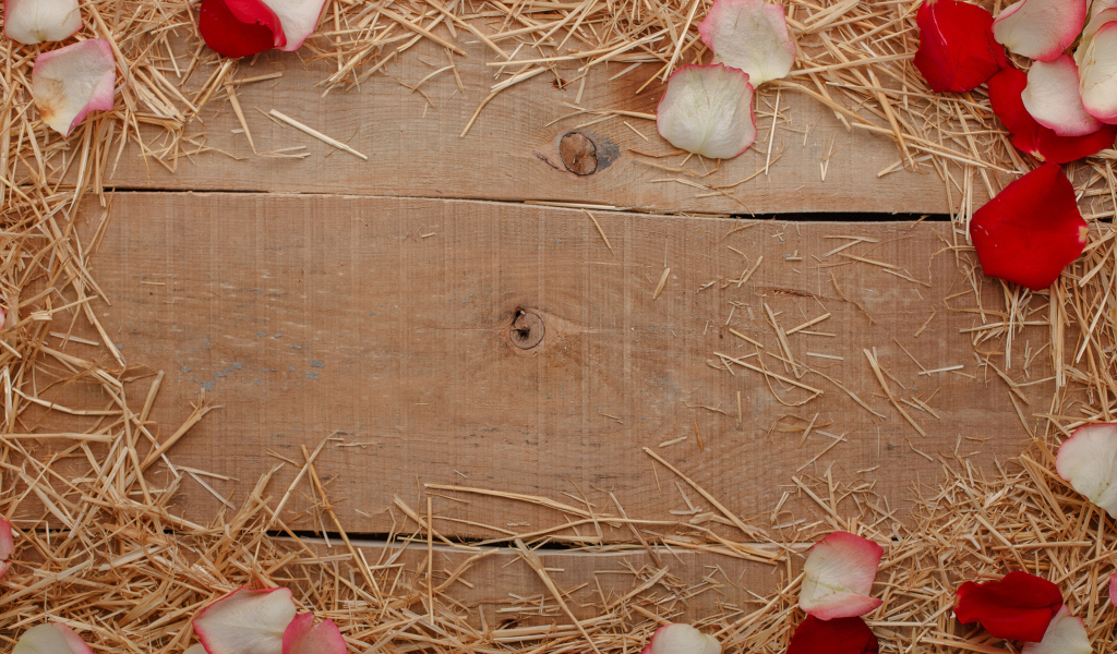 Сено и лепестки роз на деревянном столе 