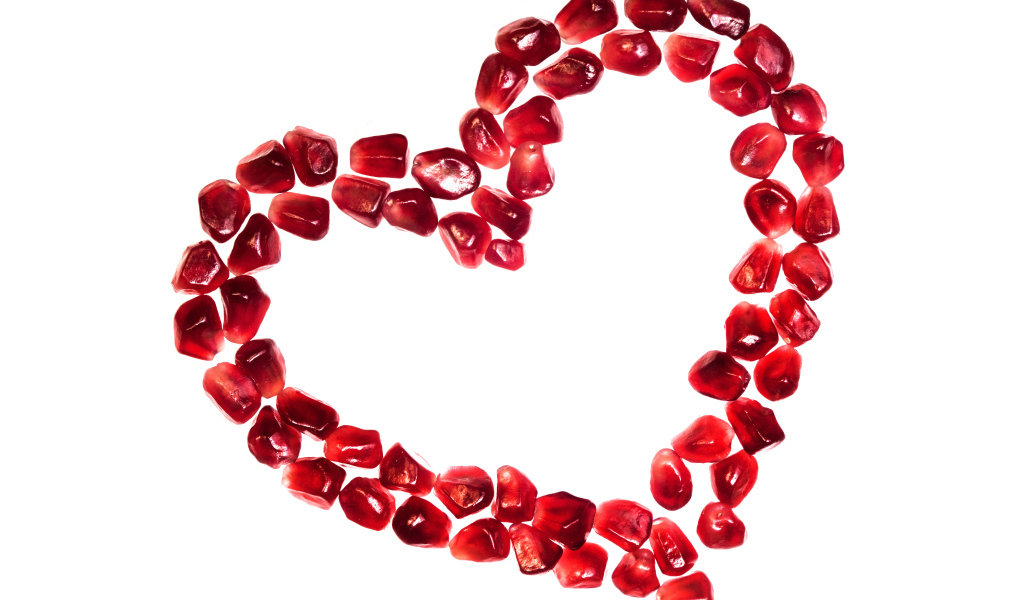 Сердце из гранатовых зерен на белом фоне