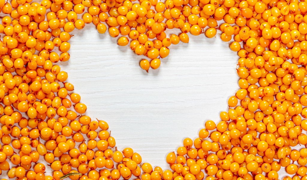 Сердце из ягод облепихи на столе 