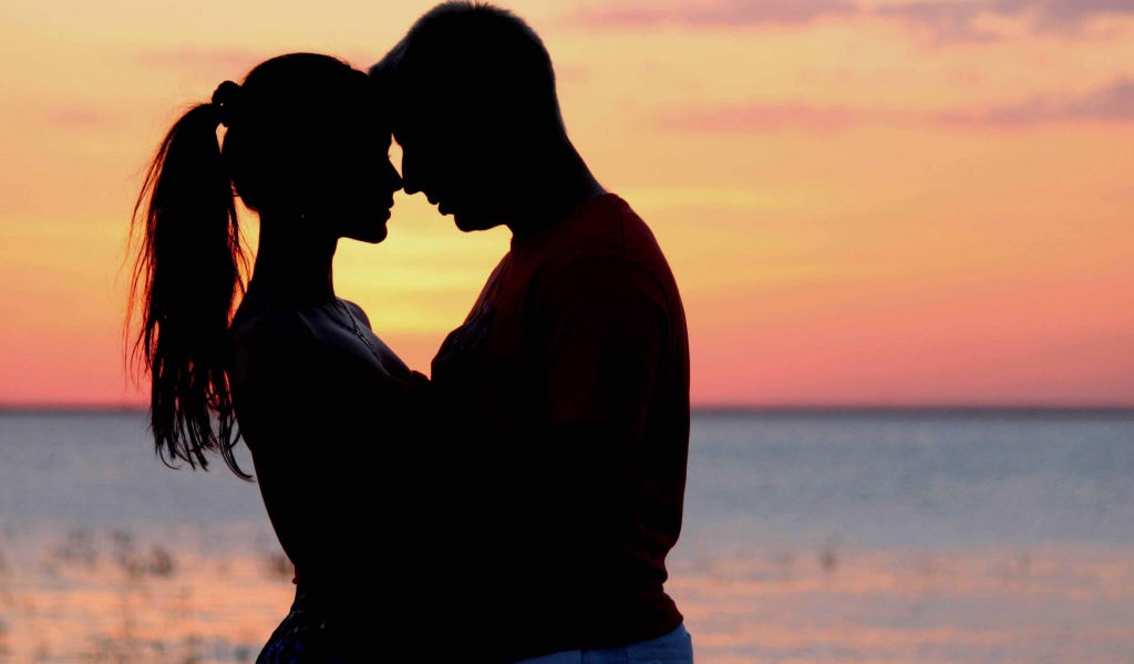 Влюбленная пара на фоне моря в сумерках 