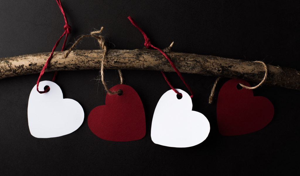 Бумажные сердечки на ветке на черном фоне