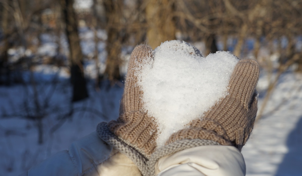 Снег в руках у девушки в перчатках 