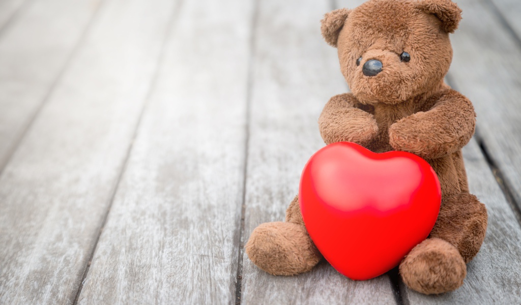 Медвежонок Тедди с красным сердцем сидит на столе