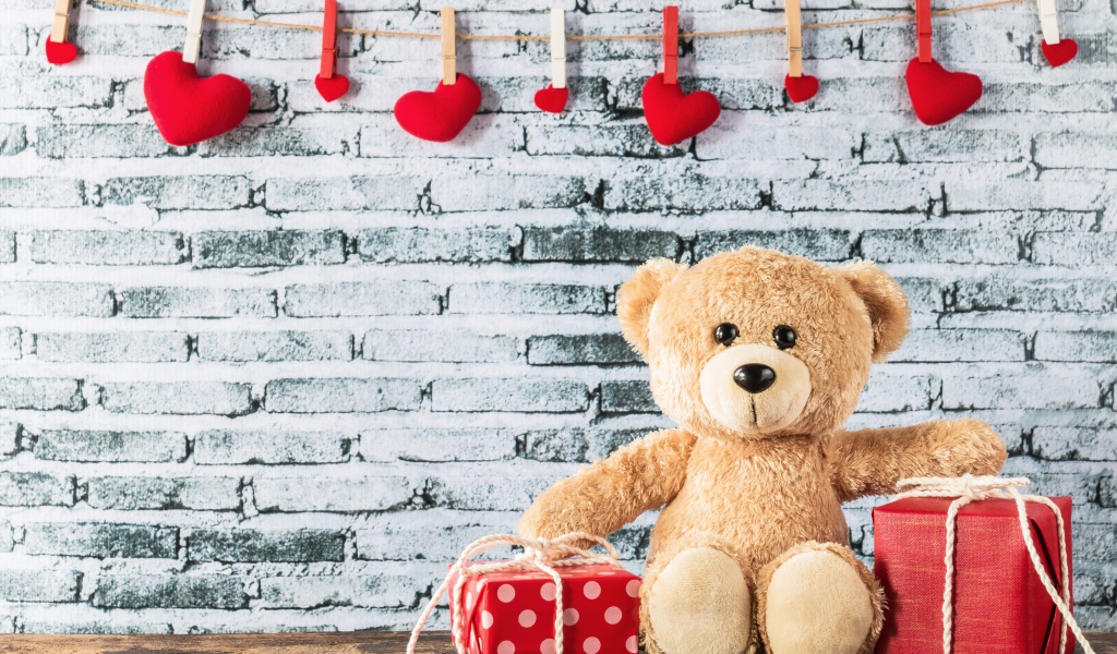 Медвежонок Тедди с подарками на фоне стены с сердечками