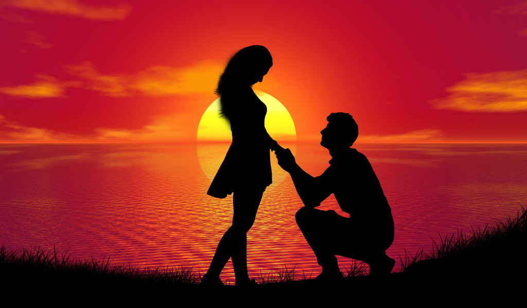 Парень делает девушке предложение на фоне заката у моря