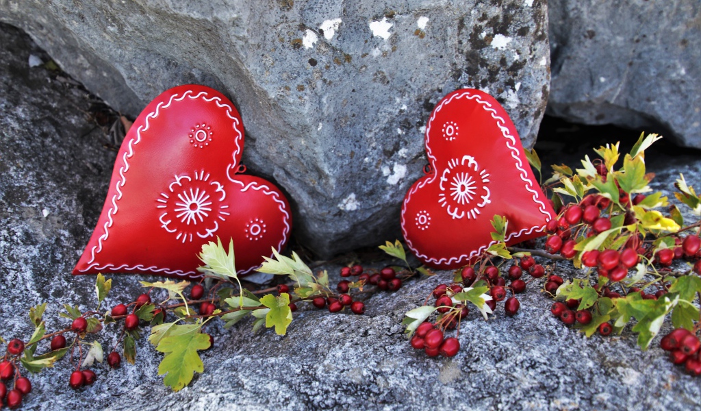 Два сердца лежат у камня с красными ягодами