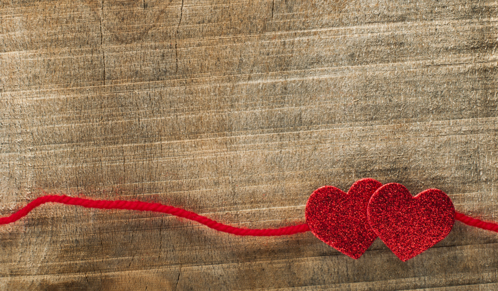 Two red hearts with a lace on a wooden background