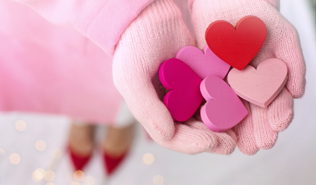 Деревянные сердечки в руках девушки в розовых перчатках 