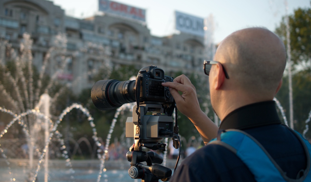 Мужчина снимает на камеру фонтан в парке