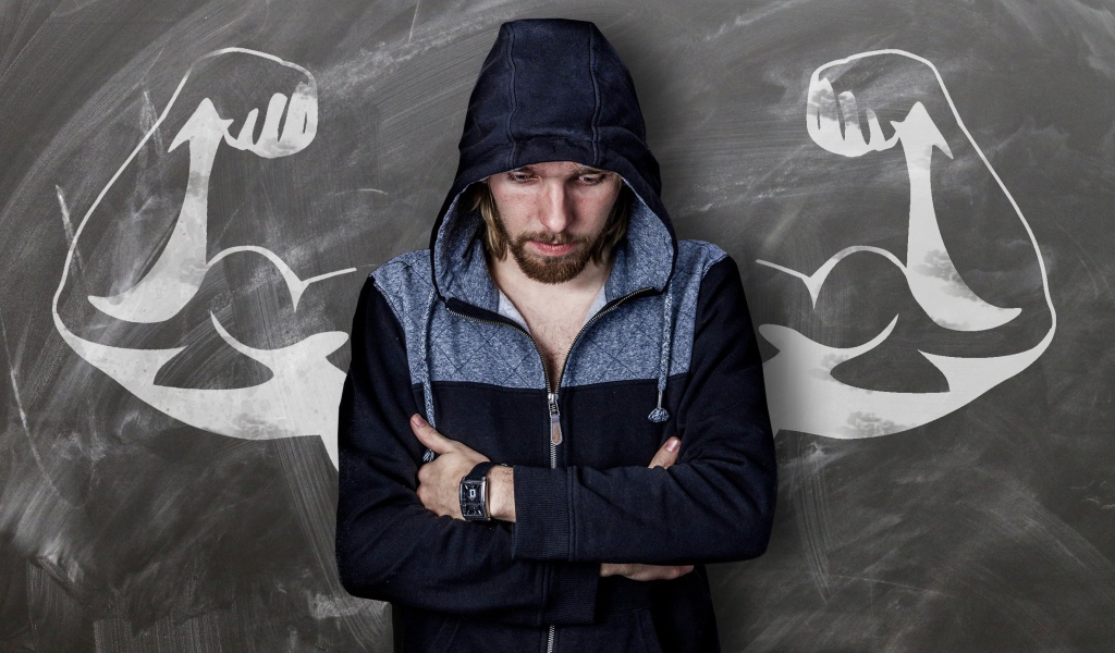 Мужчина с часами на руке грустит у стены