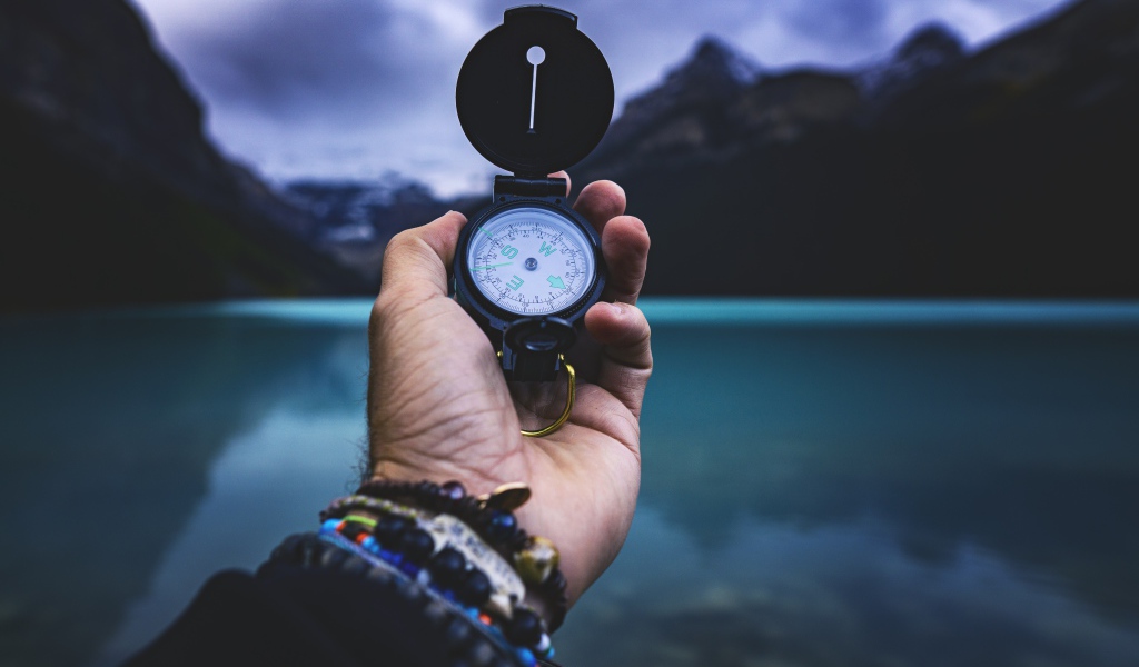 Компас в руке у мужчины на фоне гор 