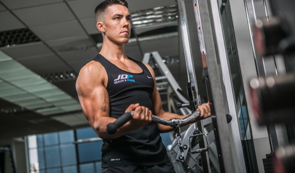Накаченный мужчина занимается на тренажере в спортзале