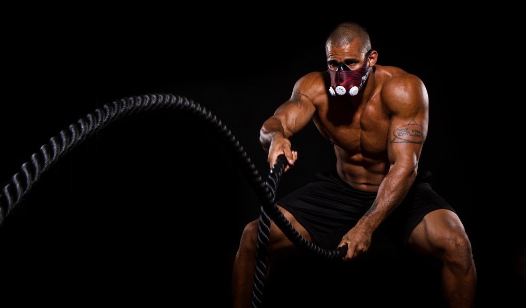 Накаченный мужчина в маске с канатом в руках 