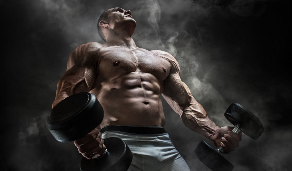 Мужчина бодибилдер с тяжелыми гантелями в руках