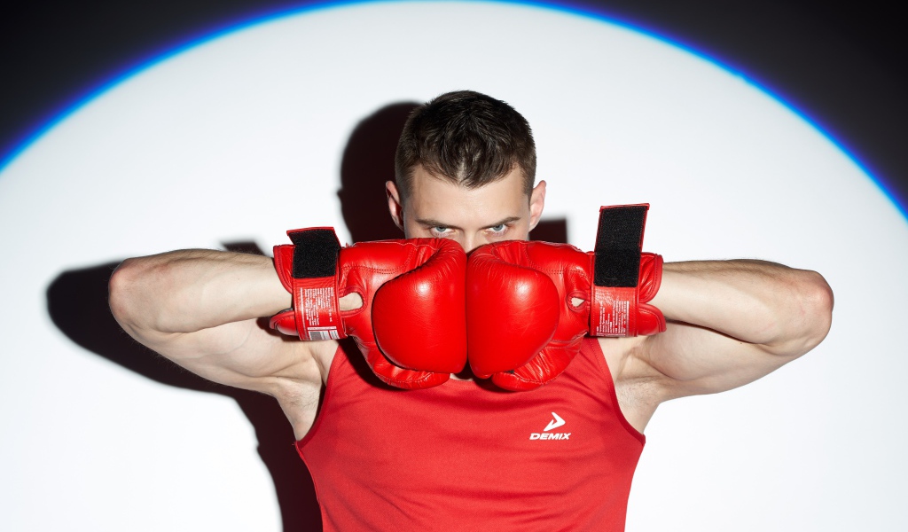Мужчина боксер с красных перчатках в свете прожектора 