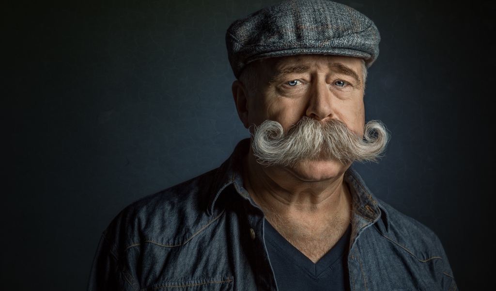 Мужчина в кепке с большими усами на лице 