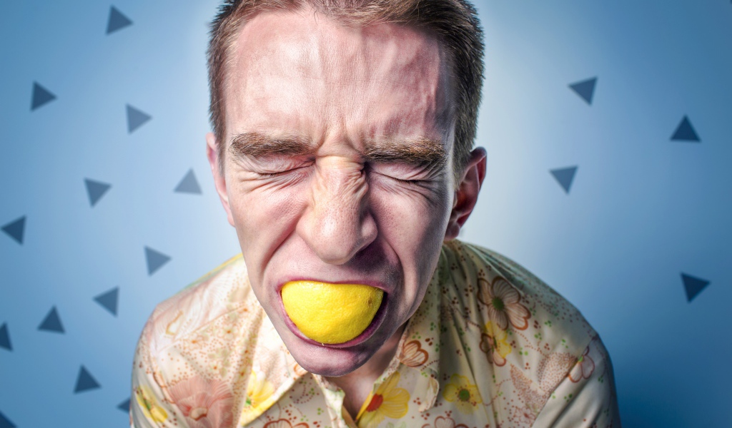 Man with closed eyes eating lemon