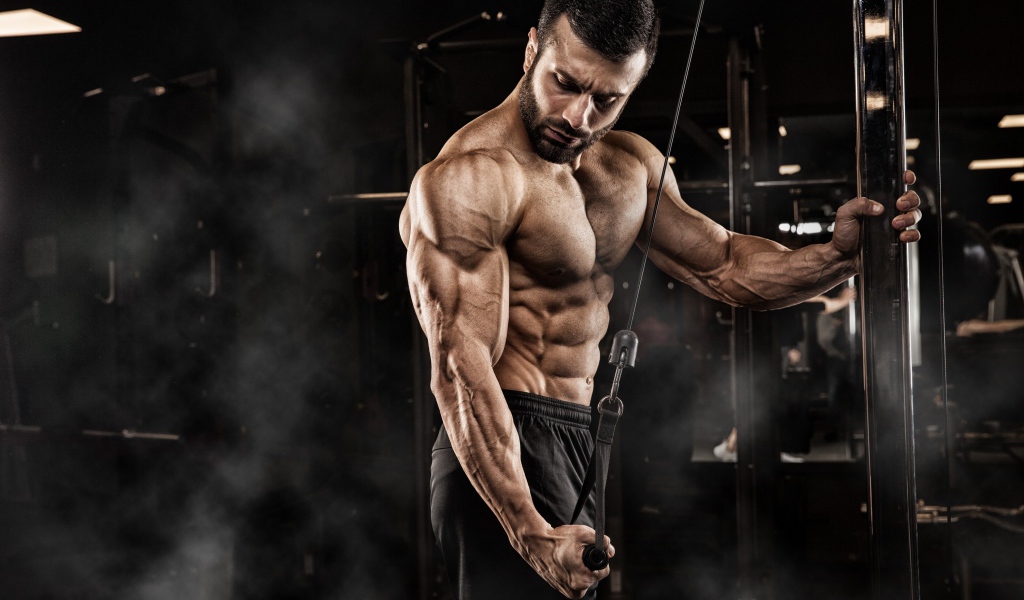 Сильный мужчина бодибилдер в спортзале