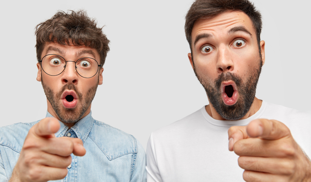 Два удивленных мужчины на сером фоне