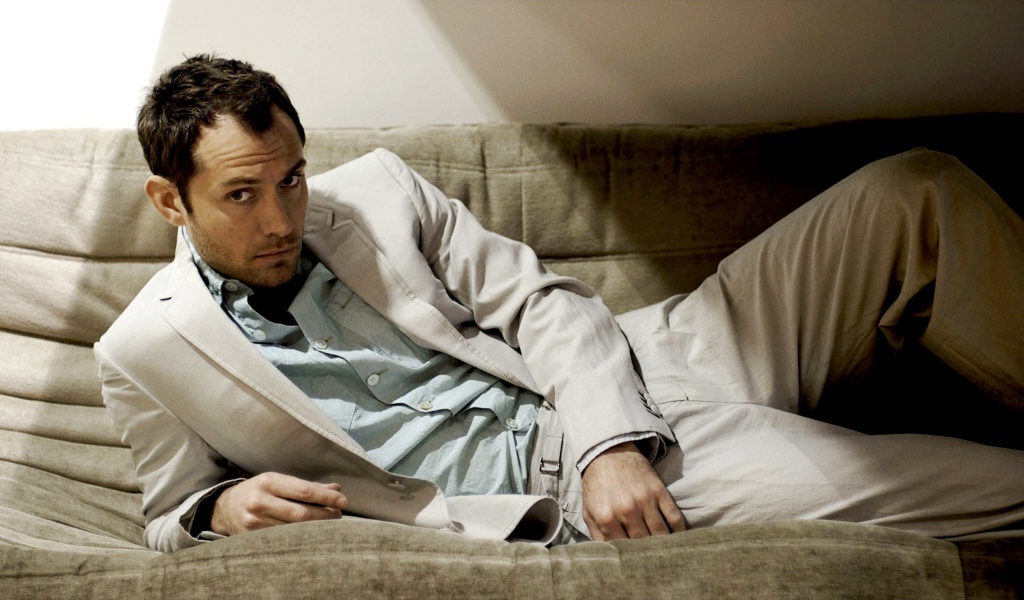 Британский актер Джуд Лоу в костюме лежит на диване