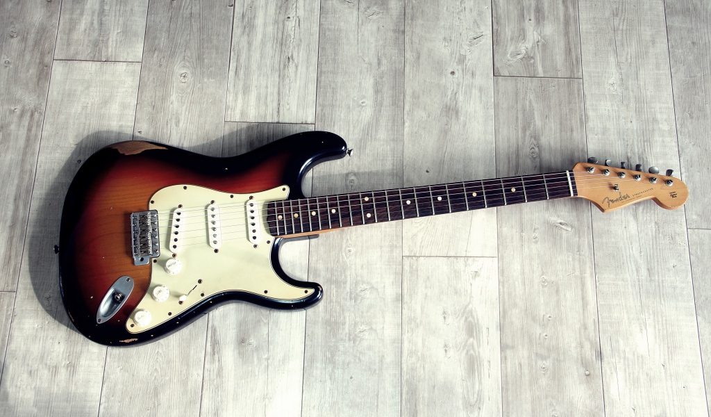 Электрогитара лежит на деревянном полу