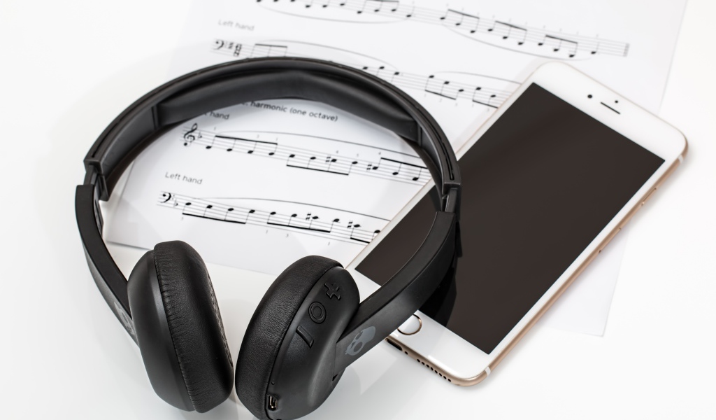 Наушники на столе с нотами и смартфоном