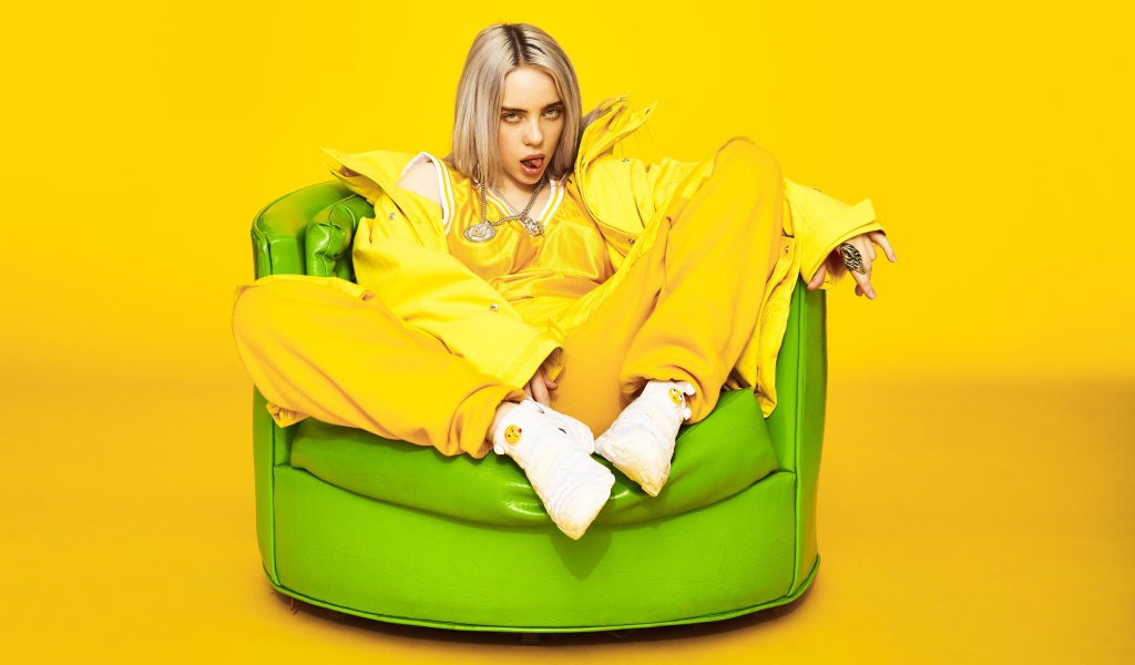 Певица Билли Айлиш сидит в кресле на желтом фоне