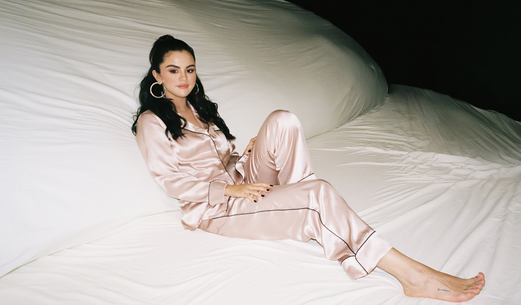 Певица Селена Гомез в пижаме на большой белой кровати