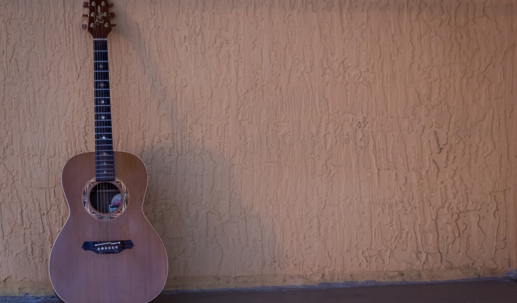 Шестиструнная гитара стоит у стены